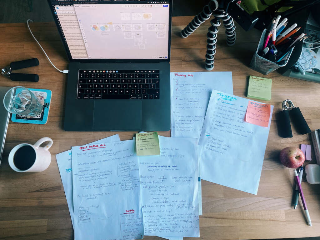 Photo taken from above of my desk with laptop and all sorts of notes on paper